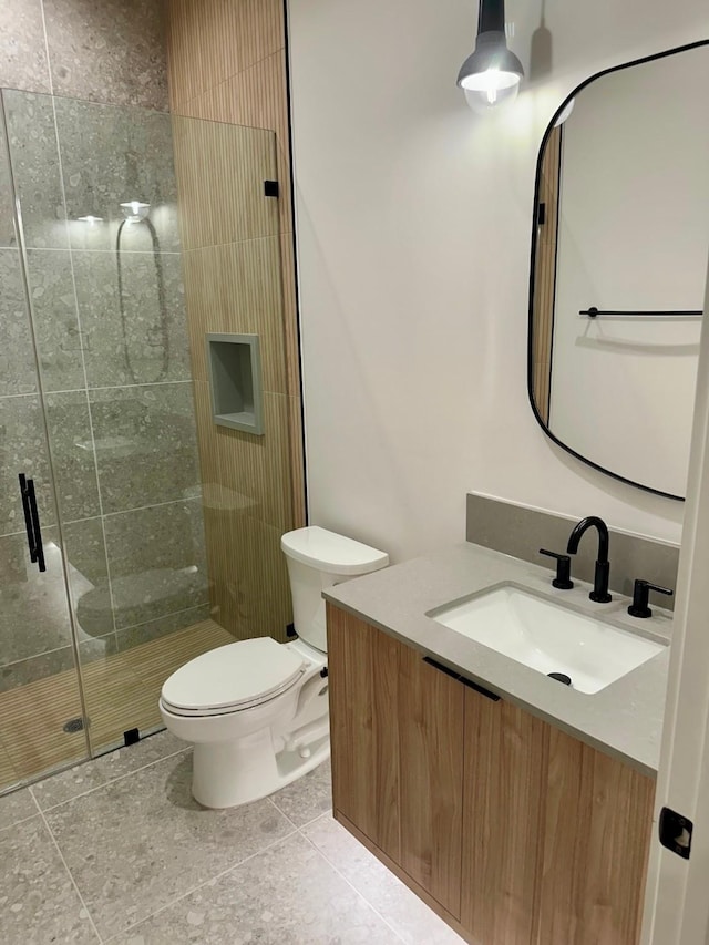 bathroom with a shower with door, vanity, tile patterned flooring, and toilet