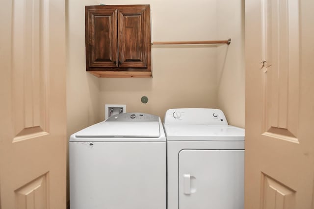 clothes washing area featuring cabinets and washer and clothes dryer