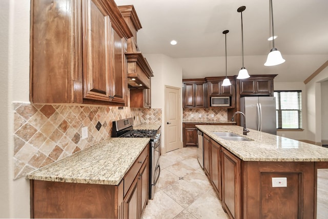 kitchen featuring sink, light stone counters, decorative light fixtures, stainless steel appliances, and a kitchen island with sink