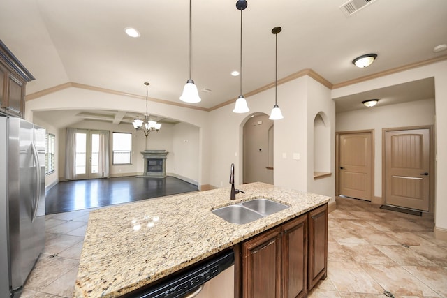 kitchen featuring sink, stainless steel appliances, light stone counters, an island with sink, and decorative light fixtures