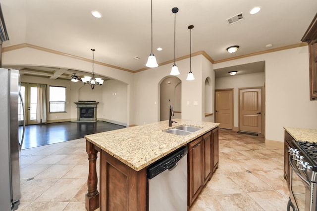 kitchen with appliances with stainless steel finishes, decorative light fixtures, sink, light stone countertops, and a center island with sink