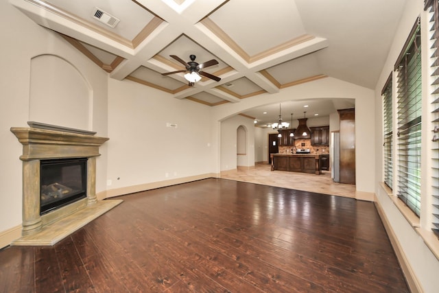 unfurnished living room with a wealth of natural light, a fireplace, beamed ceiling, coffered ceiling, and light hardwood / wood-style floors