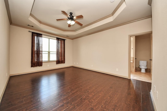 spare room with dark wood-type flooring, ceiling fan, a tray ceiling, and crown molding