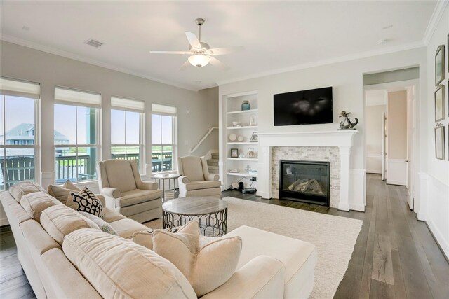 living room with crown molding, built in shelves, dark hardwood / wood-style floors, and ceiling fan