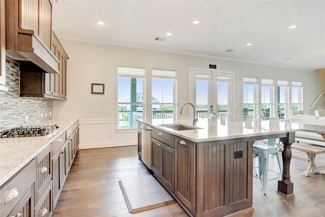 kitchen featuring sink, appliances with stainless steel finishes, an island with sink, a kitchen bar, and decorative backsplash