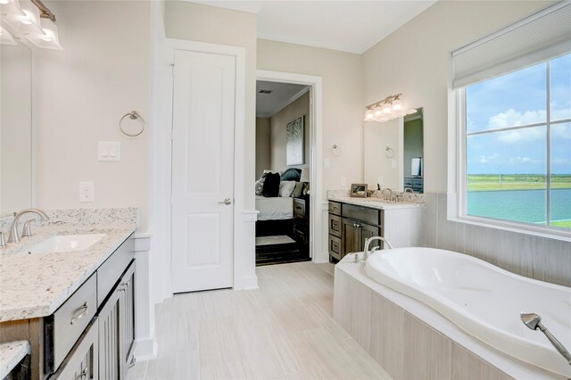 bathroom with vanity, tiled tub, and a water view