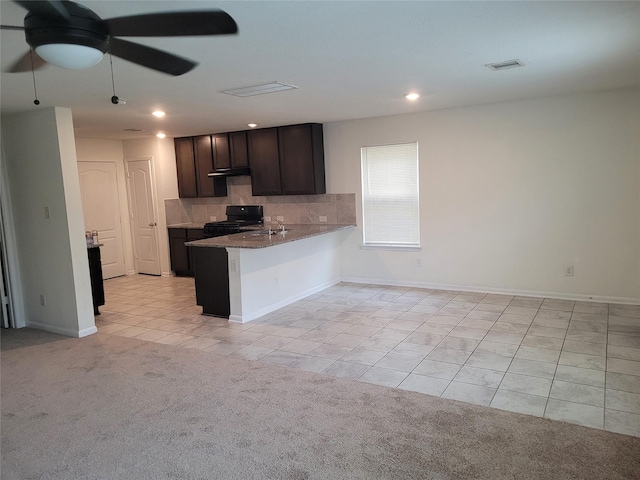 kitchen with black range oven, backsplash, light colored carpet, dark brown cabinetry, and kitchen peninsula