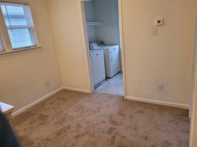 interior space featuring light tile patterned floors, washer and clothes dryer, baseboards, and light carpet
