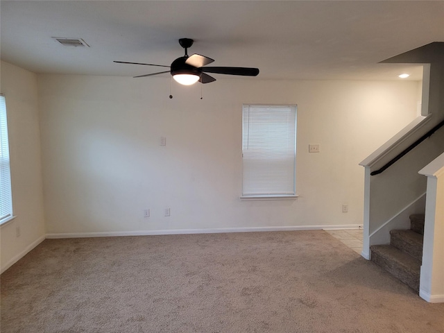 unfurnished living room featuring stairway, carpet flooring, a ceiling fan, baseboards, and visible vents