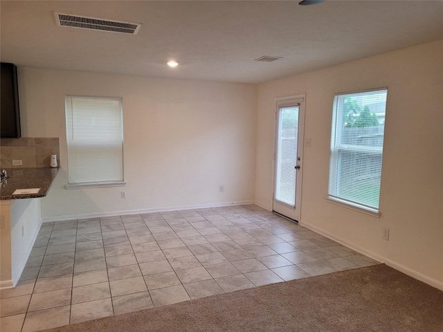 spare room featuring recessed lighting, light tile patterned floors, baseboards, visible vents, and light carpet