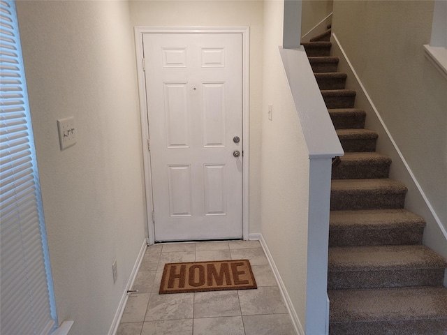doorway to outside with baseboards, stairs, and light tile patterned flooring