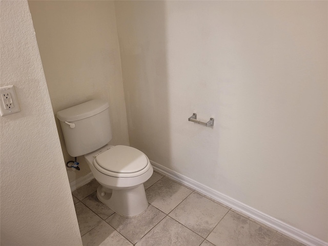 bathroom with baseboards, toilet, and tile patterned flooring