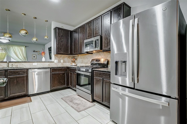 kitchen with appliances with stainless steel finishes, decorative light fixtures, sink, backsplash, and light stone counters