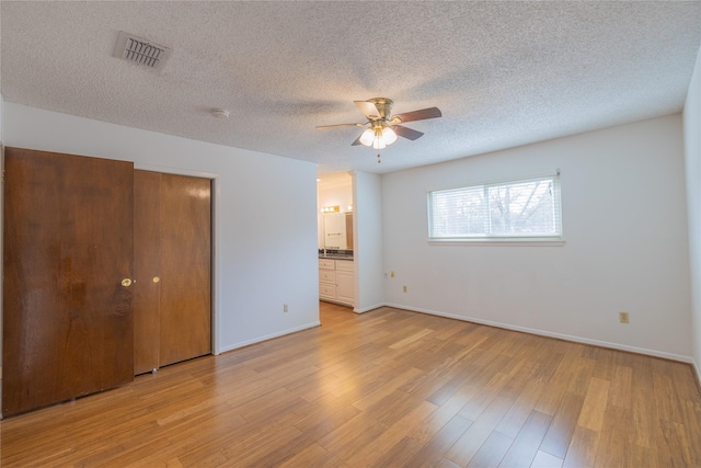 unfurnished bedroom with connected bathroom, light hardwood / wood-style floors, a textured ceiling, and ceiling fan