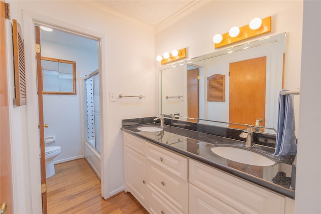 full bathroom featuring shower / bath combination with glass door, hardwood / wood-style flooring, vanity, toilet, and crown molding