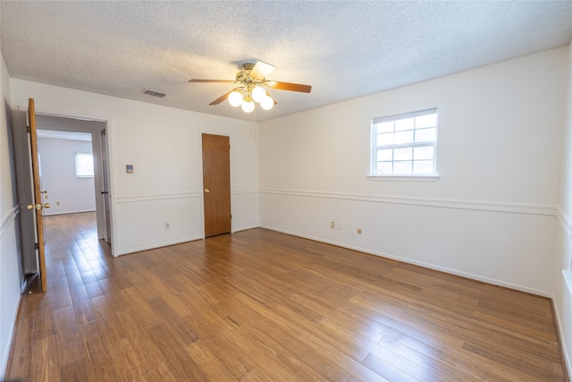 empty room featuring ceiling fan, wood-type flooring, and a textured ceiling