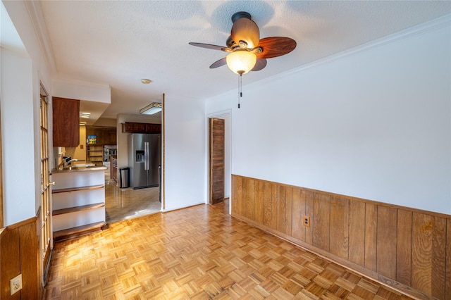 unfurnished room with wood walls, sink, a textured ceiling, and light parquet floors