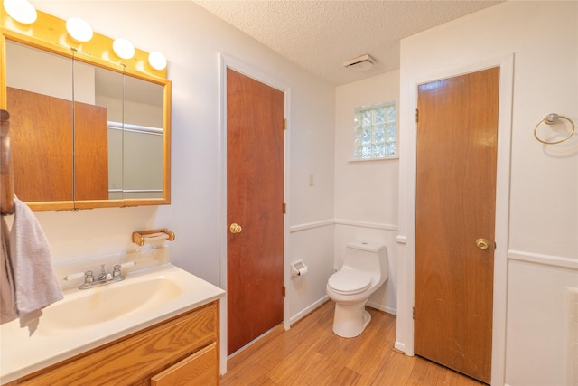 bathroom featuring hardwood / wood-style flooring, vanity, a textured ceiling, and toilet