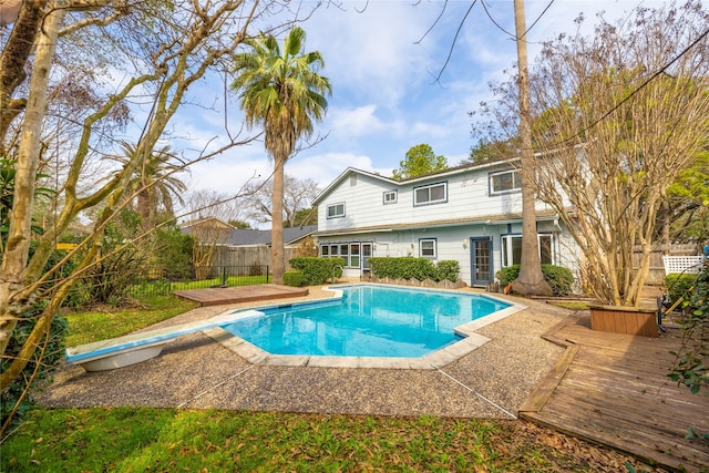 view of pool with a wooden deck and a diving board