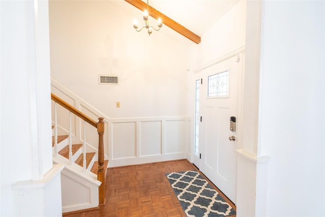 entrance foyer featuring lofted ceiling with beams, parquet flooring, and a notable chandelier