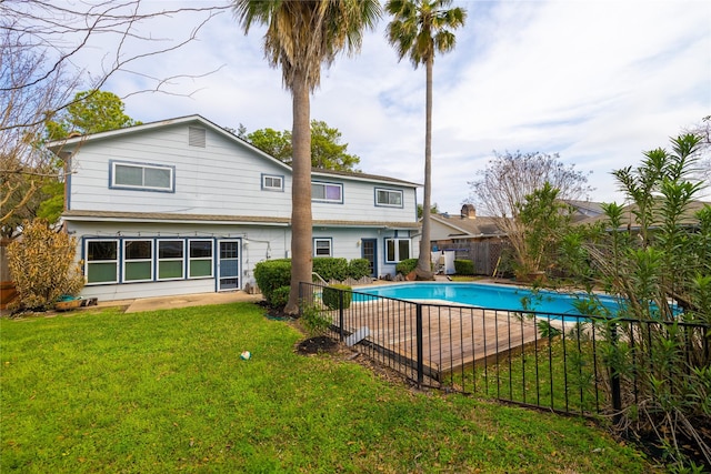 rear view of property featuring a fenced in pool and a lawn