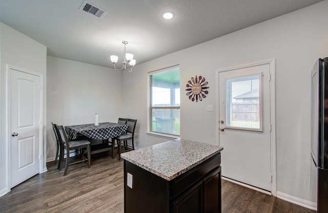 kitchen with dark brown cabinetry, a kitchen island, dark hardwood / wood-style flooring, decorative light fixtures, and a chandelier