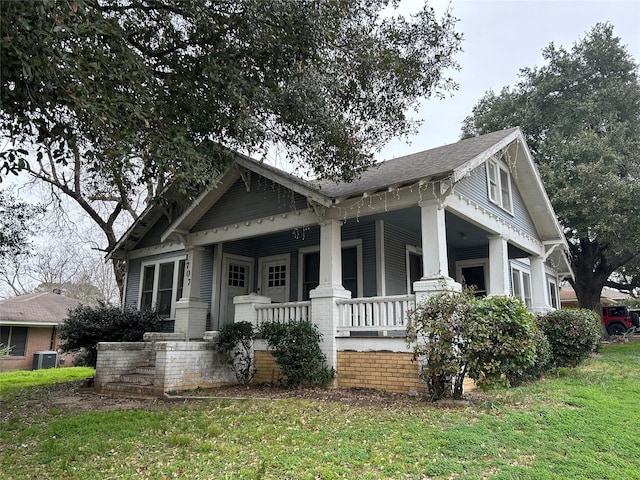 view of front of home with cooling unit, covered porch, and a front lawn