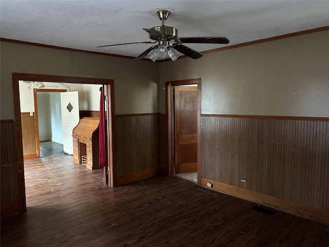 unfurnished room featuring hardwood / wood-style flooring, ceiling fan, ornamental molding, a textured ceiling, and wood walls