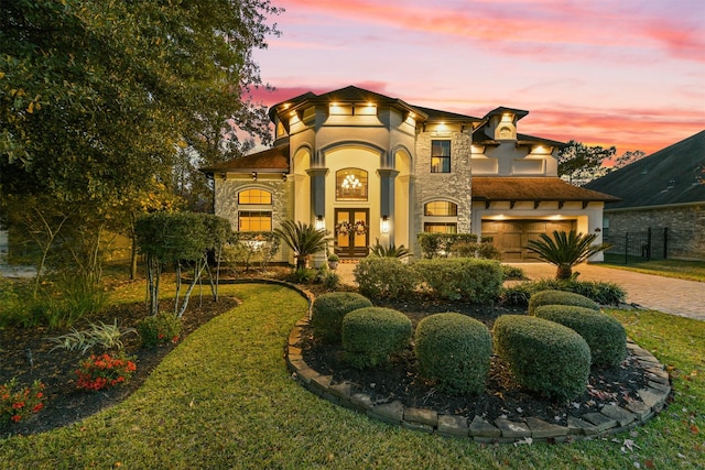 mediterranean / spanish house with stone siding, stucco siding, french doors, and driveway