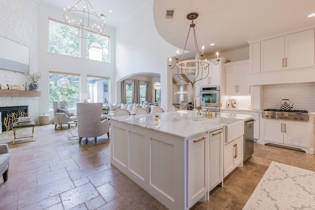 kitchen featuring stone tile floors, open floor plan, appliances with stainless steel finishes, and visible vents