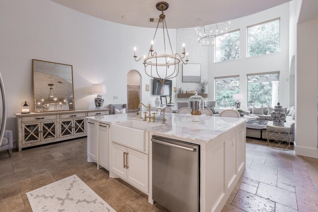 kitchen with stone tile flooring, open floor plan, dishwasher, and a high ceiling