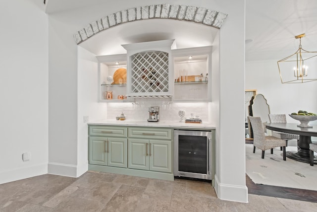 bar with baseboards, an inviting chandelier, a bar, wine cooler, and backsplash