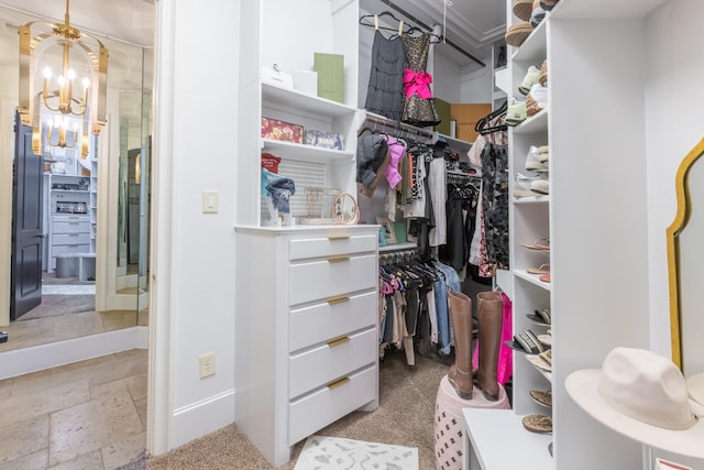 walk in closet featuring an inviting chandelier and stone tile flooring