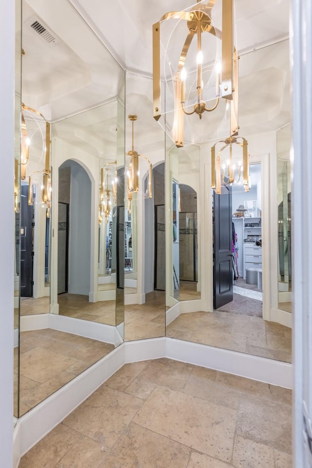 interior space with stone tile floors, a notable chandelier, and visible vents