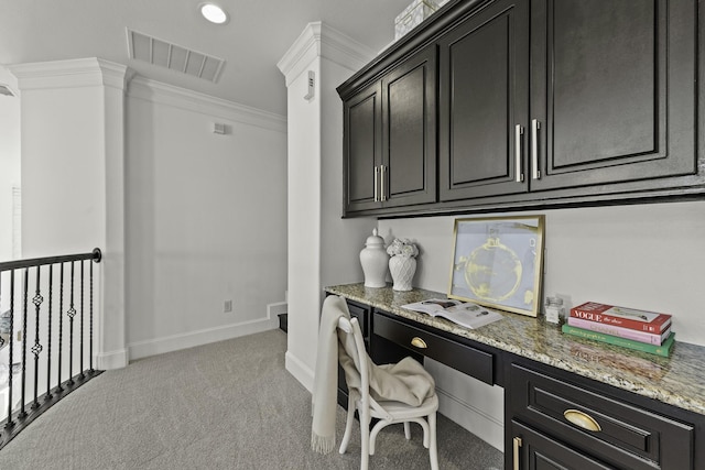 home office featuring baseboards, visible vents, ornamental molding, built in desk, and light colored carpet