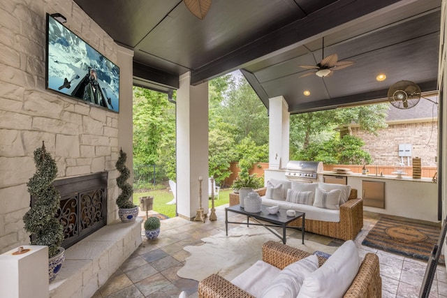 view of patio / terrace featuring area for grilling, an outdoor living space with a fireplace, a ceiling fan, and an outdoor kitchen