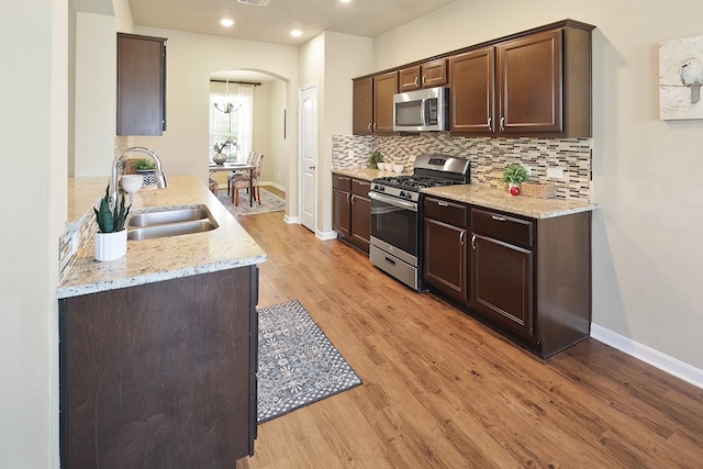 kitchen featuring stainless steel appliances, sink, decorative backsplash, and light hardwood / wood-style flooring