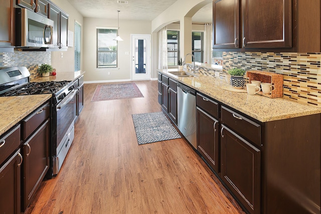 kitchen with dark brown cabinetry, hanging light fixtures, sink, and appliances with stainless steel finishes