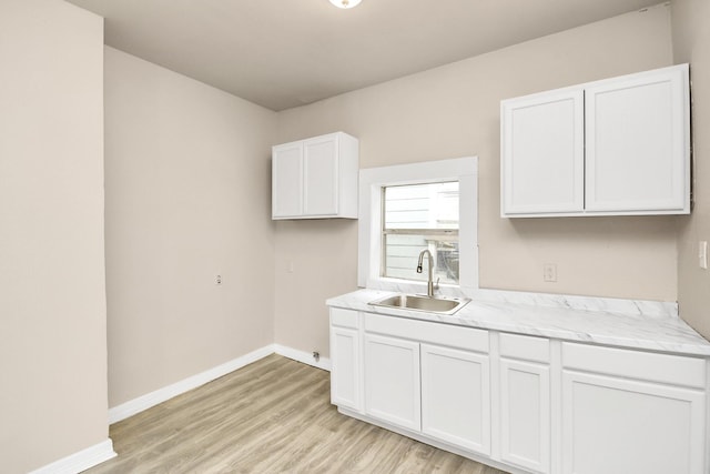 kitchen with white cabinetry, sink, and light wood-type flooring