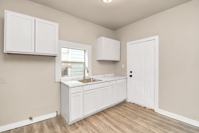 kitchen with white cabinetry, sink, and light hardwood / wood-style floors