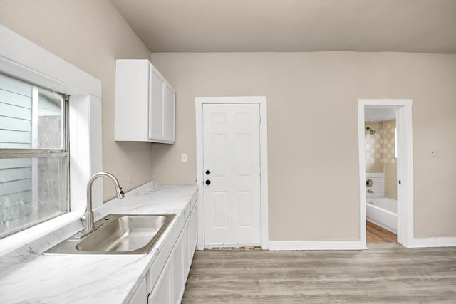 kitchen with white cabinetry, sink, and light wood-type flooring