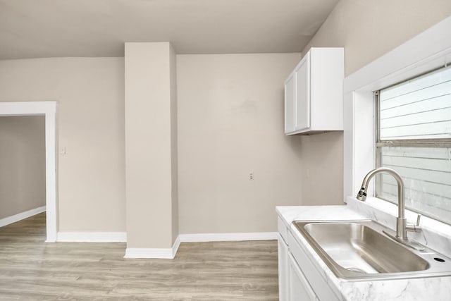 kitchen with sink, white cabinets, and light wood-type flooring