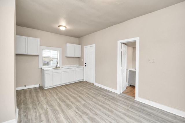 kitchen with sink, white cabinets, and light hardwood / wood-style floors