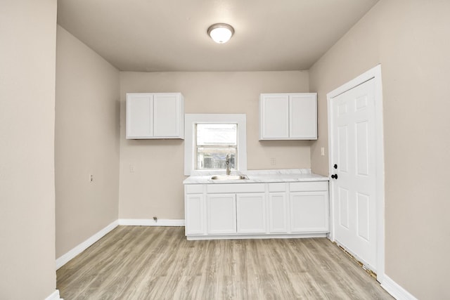 kitchen with sink, white cabinets, and light hardwood / wood-style floors