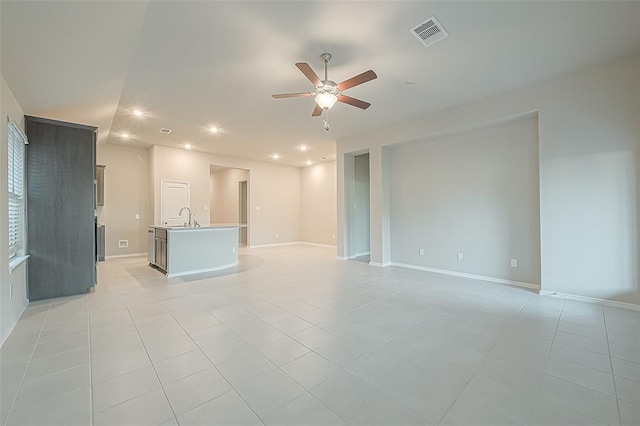 unfurnished living room with ceiling fan, sink, and light tile patterned floors