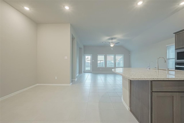 kitchen featuring sink, ceiling fan, an island with sink, light tile patterned flooring, and vaulted ceiling