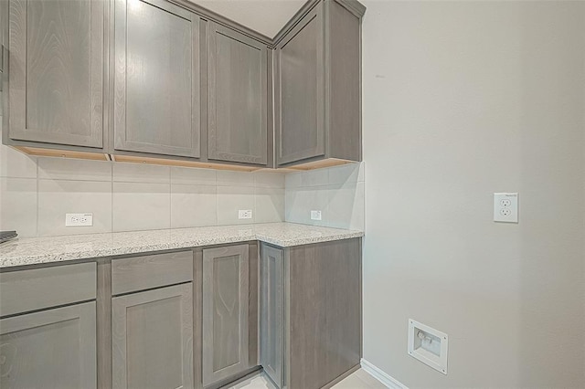 kitchen with gray cabinets, tasteful backsplash, and light stone countertops