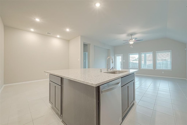 kitchen featuring dishwasher, sink, light tile patterned floors, light stone countertops, and a center island with sink