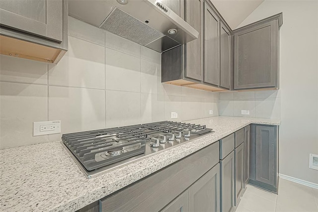 kitchen featuring extractor fan, light stone countertops, stainless steel gas cooktop, and decorative backsplash