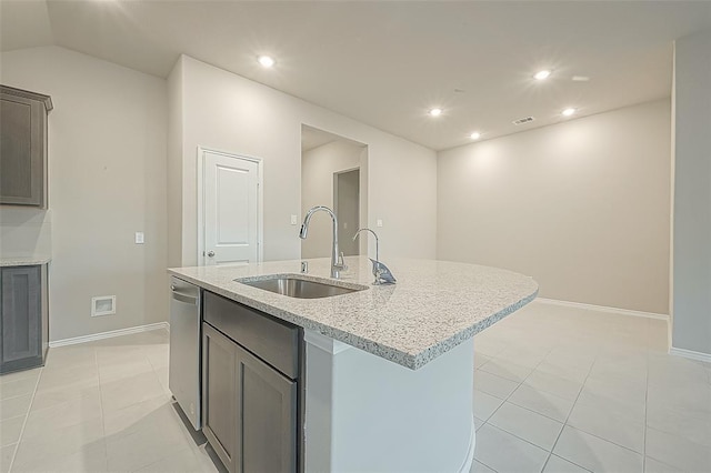 kitchen featuring an island with sink, sink, stainless steel dishwasher, light tile patterned floors, and light stone counters